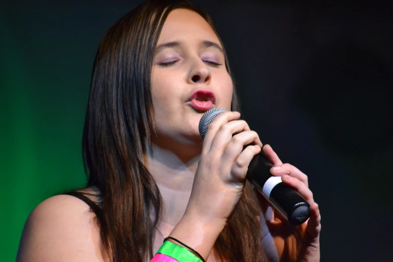 an asian woman sings into a microphone