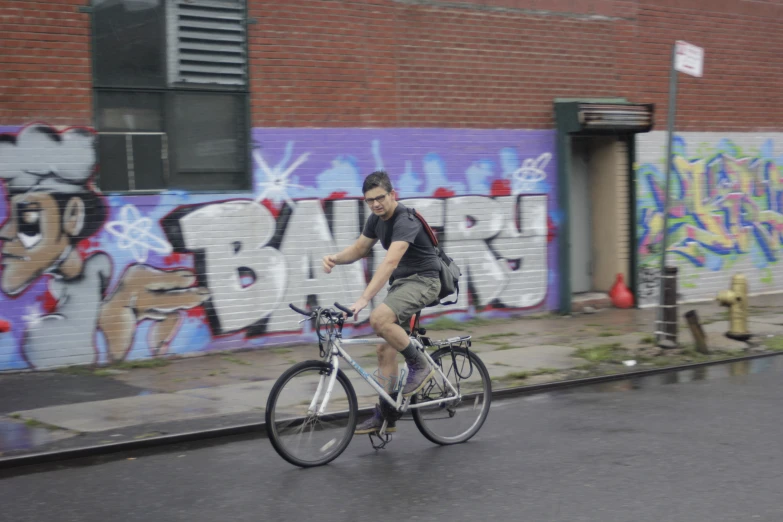 the man rides his bike in front of graffiti