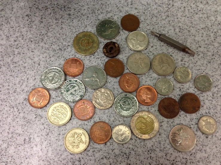 a bunch of coins laying next to a small pen