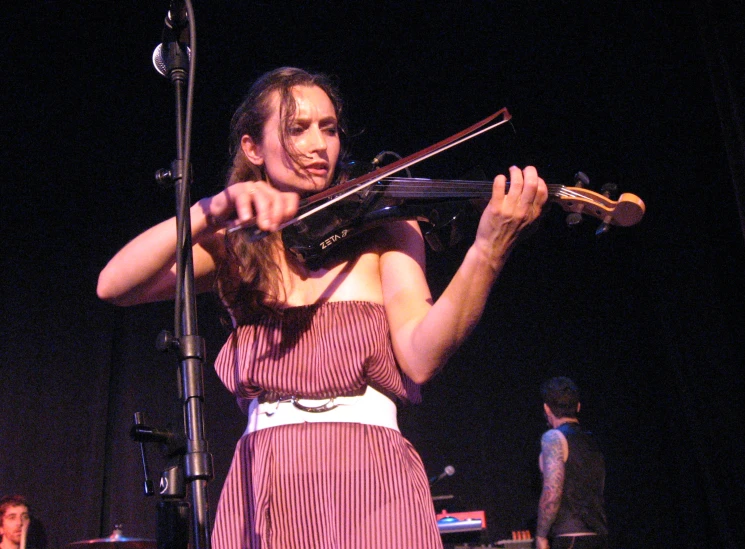 a person standing playing a violin while holding onto a ribbon