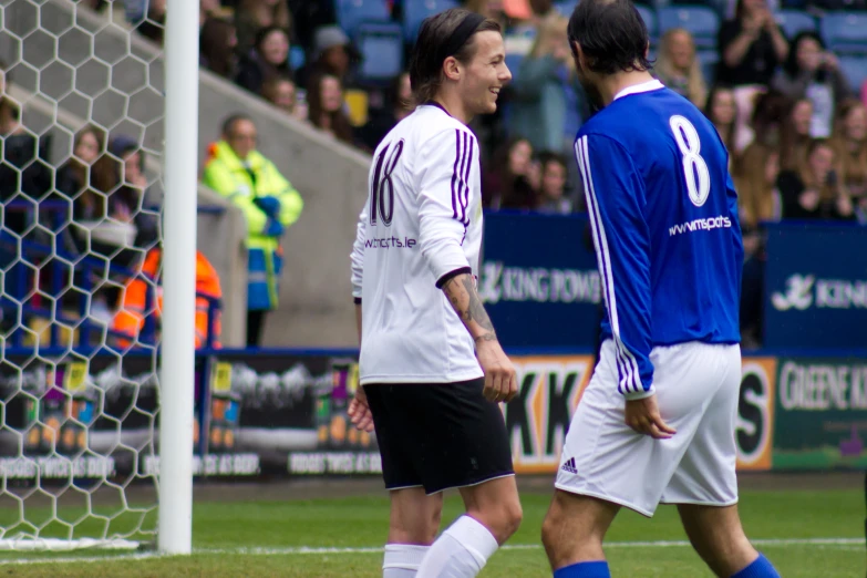 a pair of men walking around a soccer field