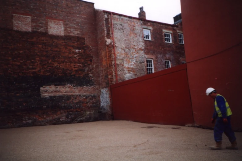 a man in safety vest next to red brick building