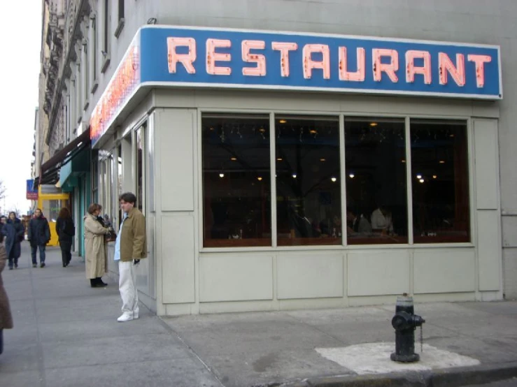 a man standing outside of a restaurant looking in the window