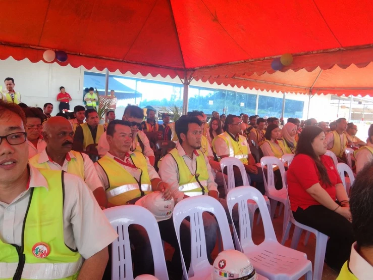 people sitting in rows, all wearing safety vests