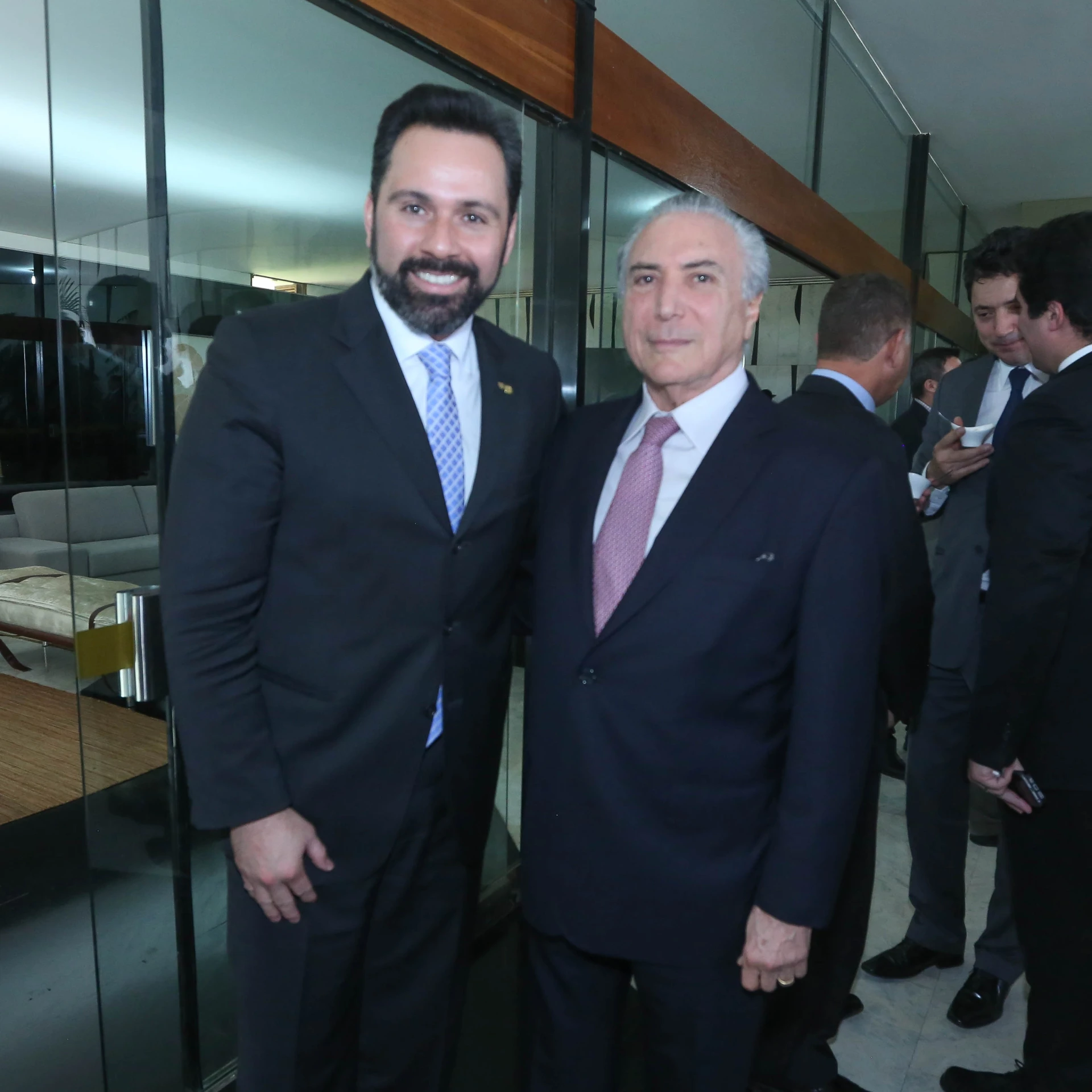 two men wearing suits posing for the camera