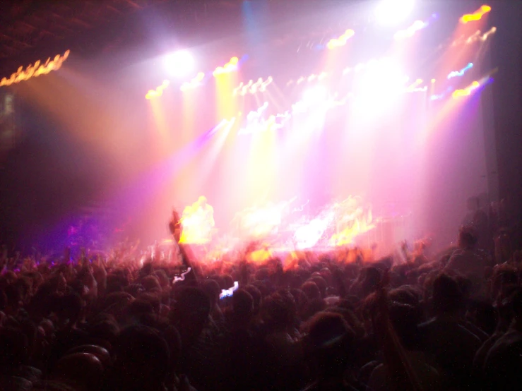 a group of people at an indoor concert with their arms in the air