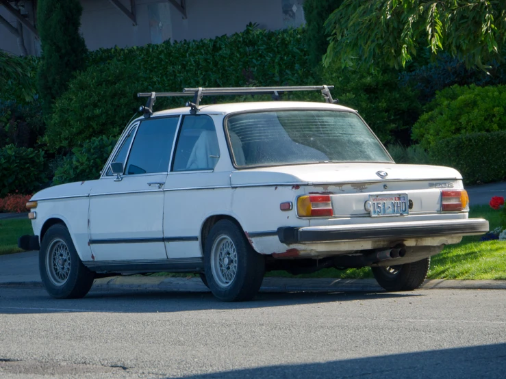 an old white car parked on the side of a street