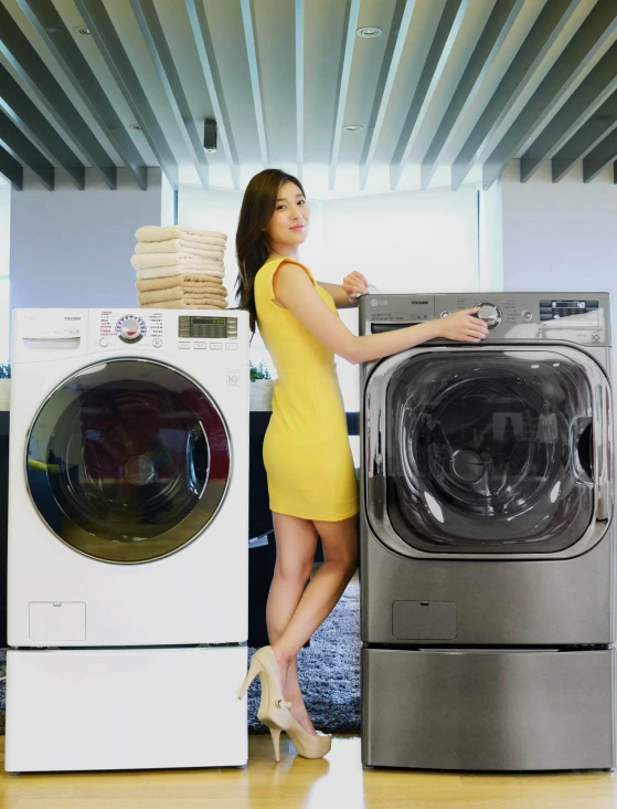 a woman is standing next to a stack of clothes near a washer