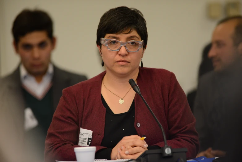 a woman speaking at a podium while two people watch