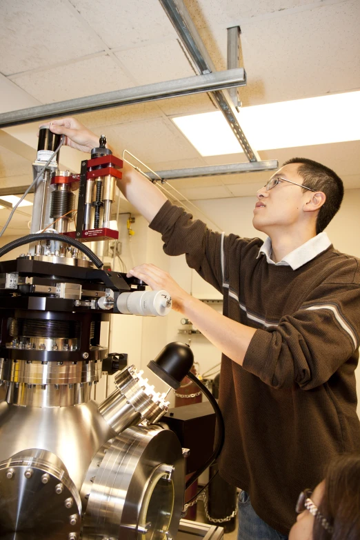 a young man looking at a machine working on it