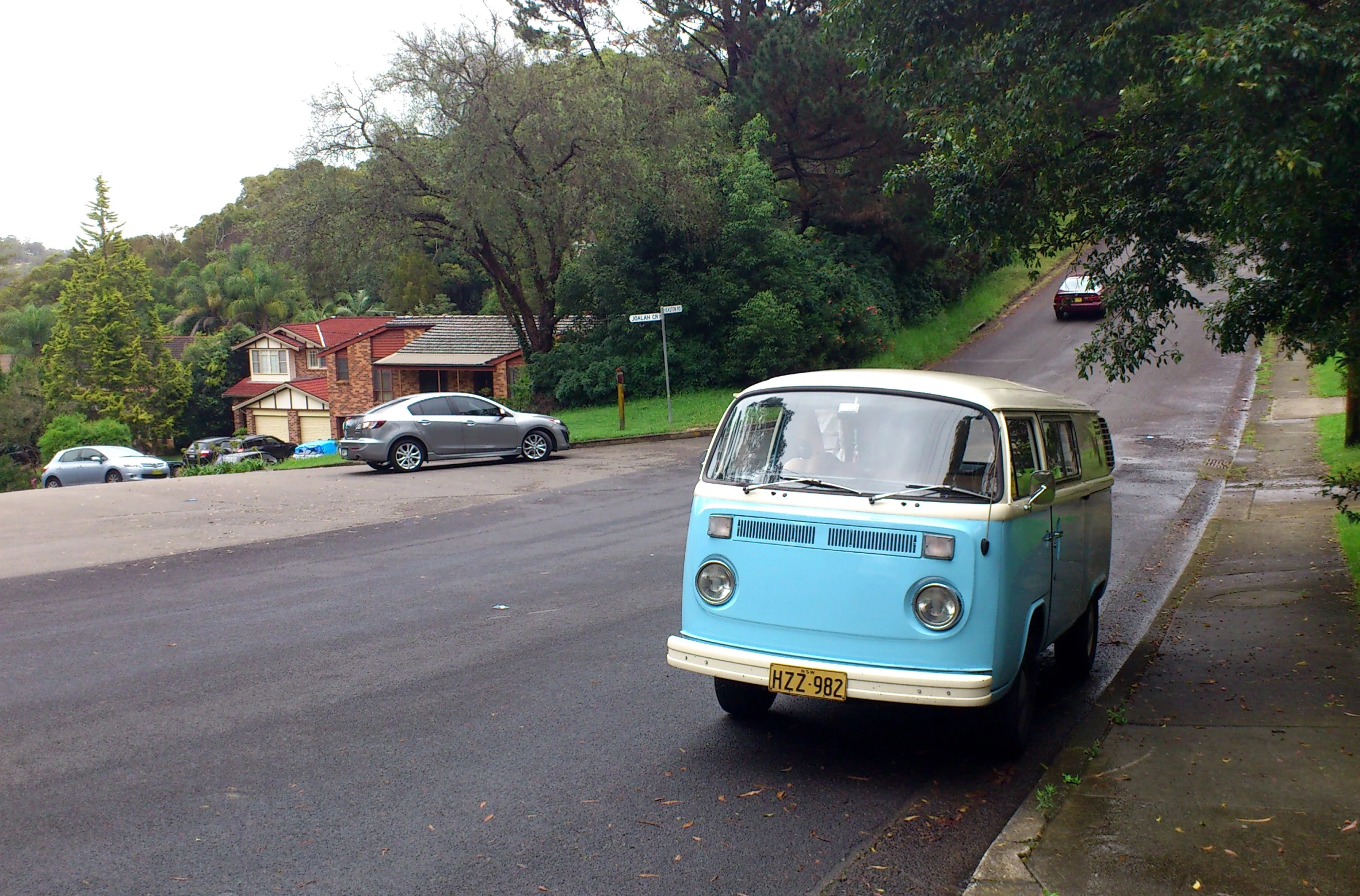 an old blue and white van parked next to a street