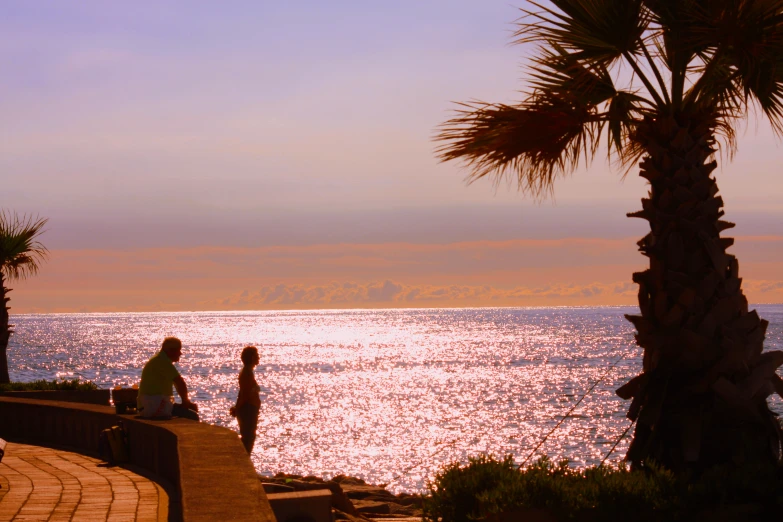 three people walking toward the ocean from a boardwalk