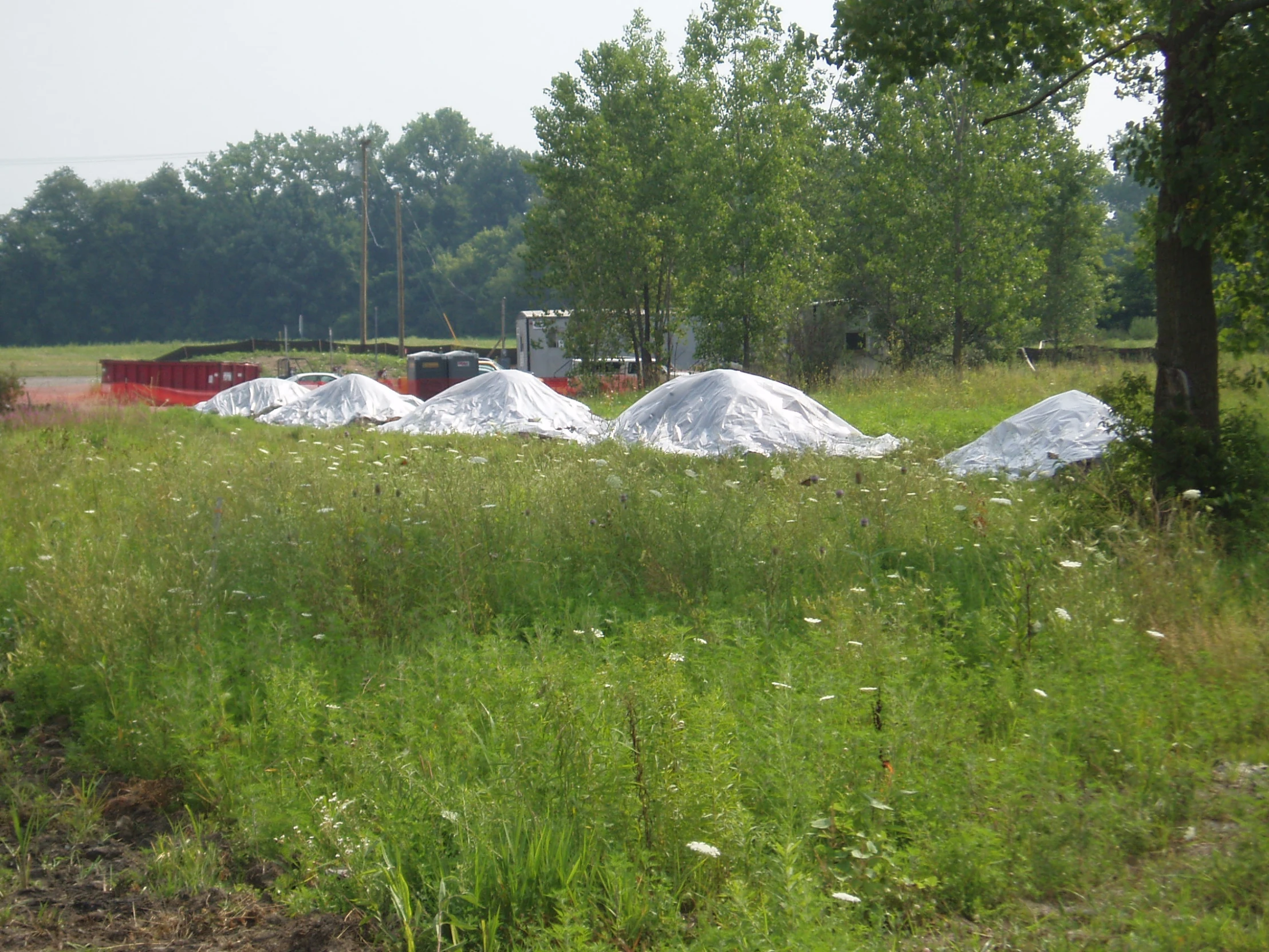 a field with mounds of sand near trees