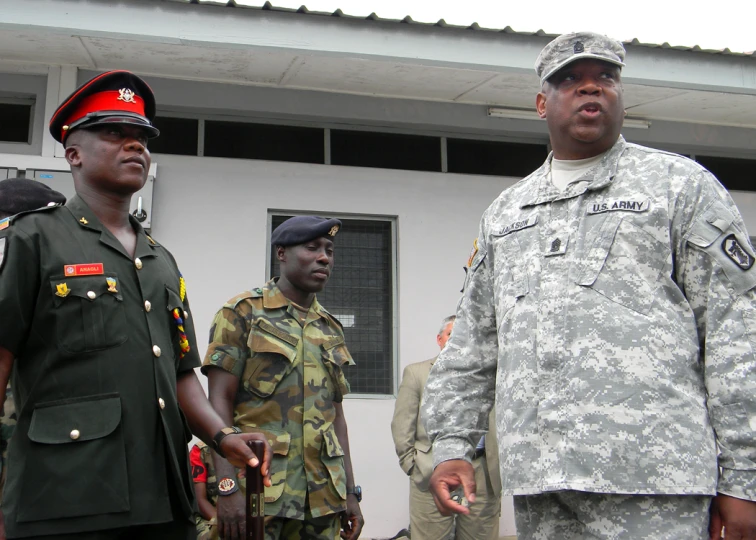 military men are standing outside with one in front wearing an army uniform