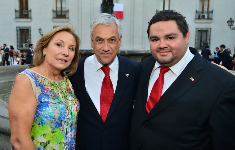 a woman standing next to two men wearing red ties