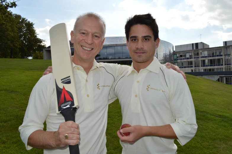 two men standing next to each other while holding a bat