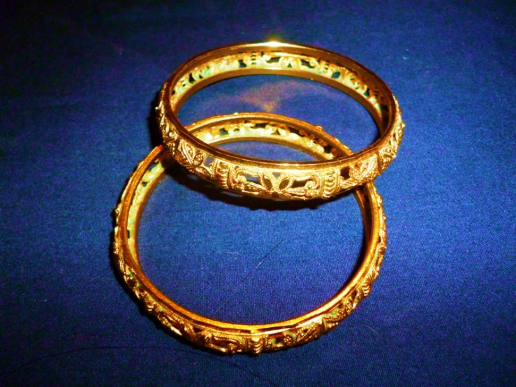 three golden rings are placed together on a blue surface