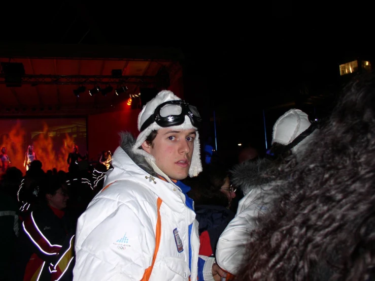 a man in white jacket and ski goggles standing next to other people