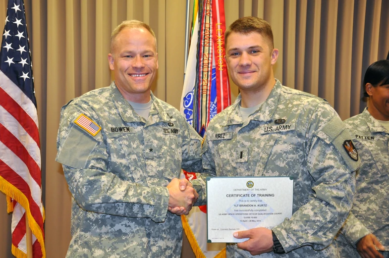 two men in military uniforms are posing for the camera with a certificate