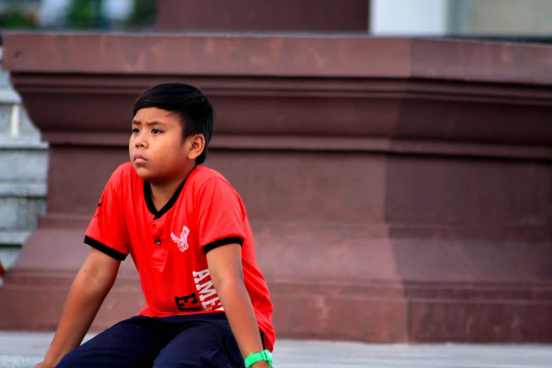 a boy sitting on top of a skateboard