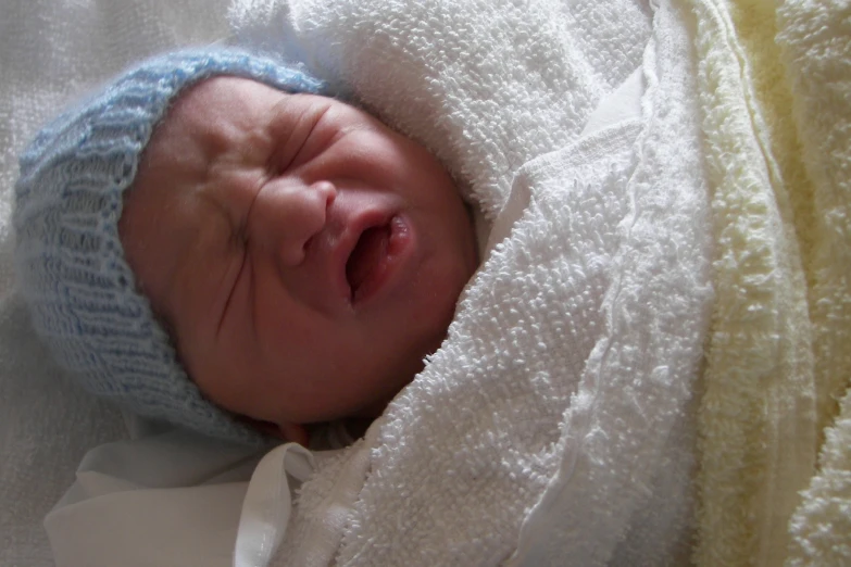 a baby in a knit hat resting his head on a blanket