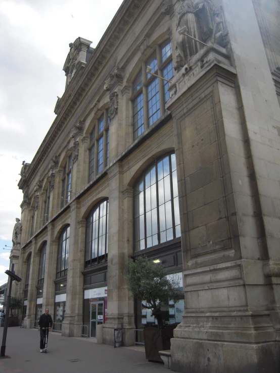 people walking by an elegant building on a cloudy day