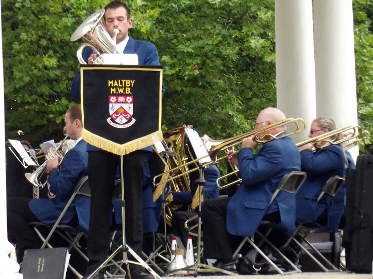 a band is playing outside with the conductor and musicians