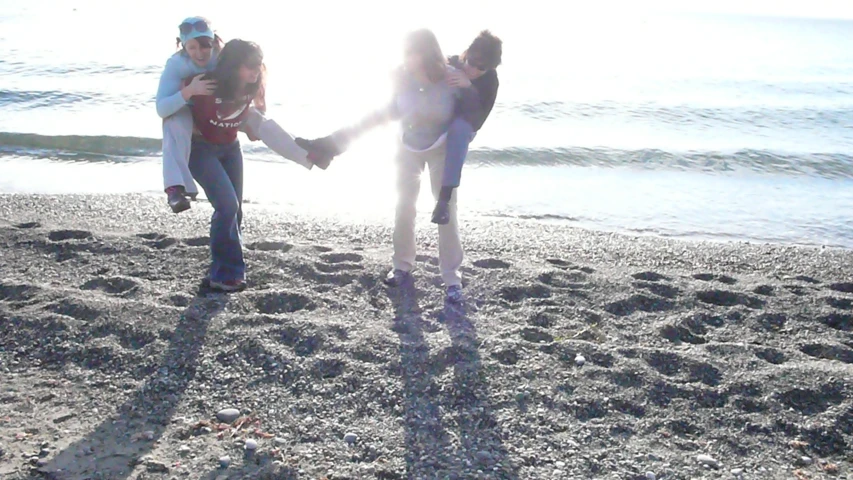 a man holds the hands of two women while she holds her on a beach