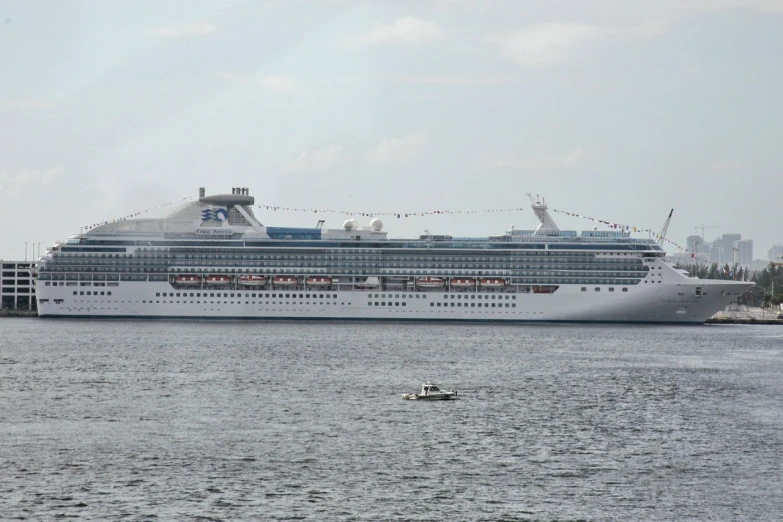 a cruise ship sits at dock with a man paddleboat