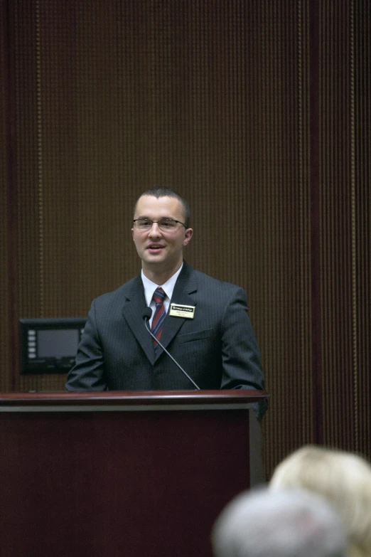 a man in a suit and tie standing at a podium