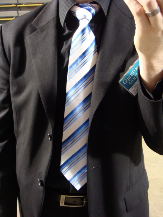 a man in a black suit is wearing a blue striped tie