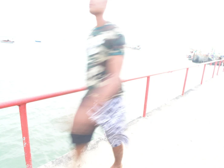 blurry man in swim shorts walking towards the ocean