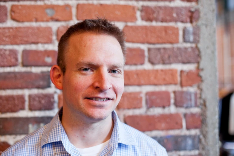 man standing in front of a brick wall