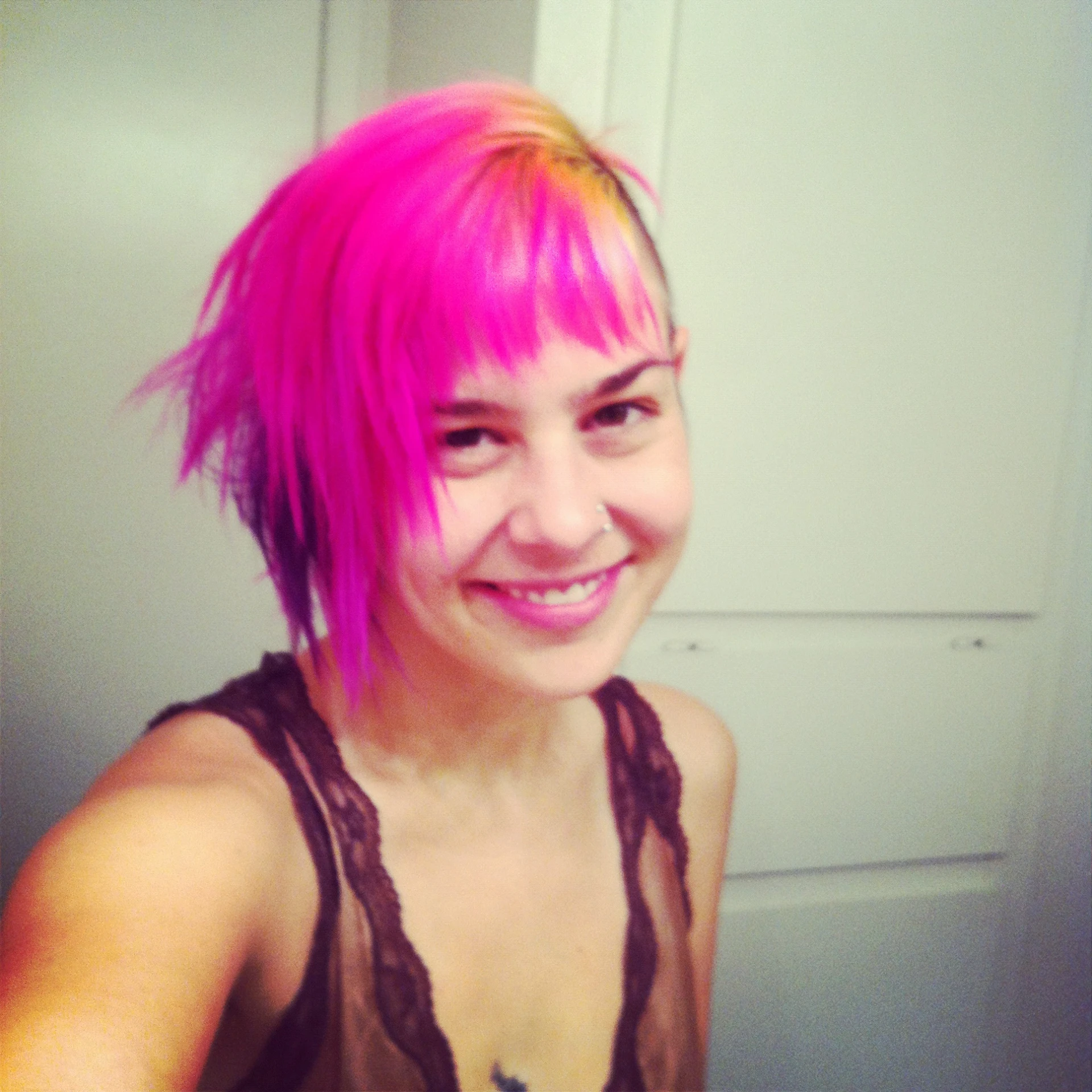 a woman with pink hair and a smile for a po