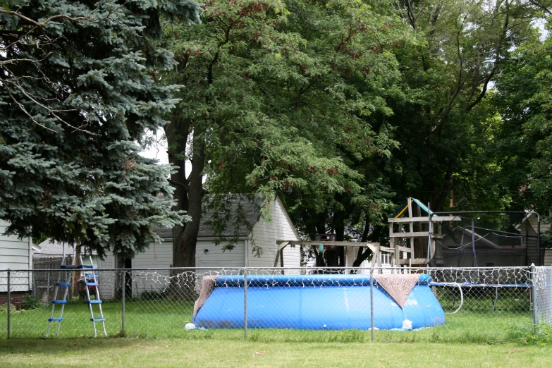 a play ground with a blue trampoline behind a fence