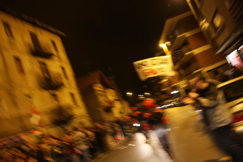 the blurred motion of people walking down a street in front of tall buildings