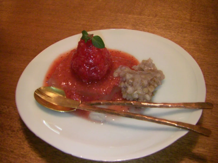 a strawberry on top of rice with spoons on a plate