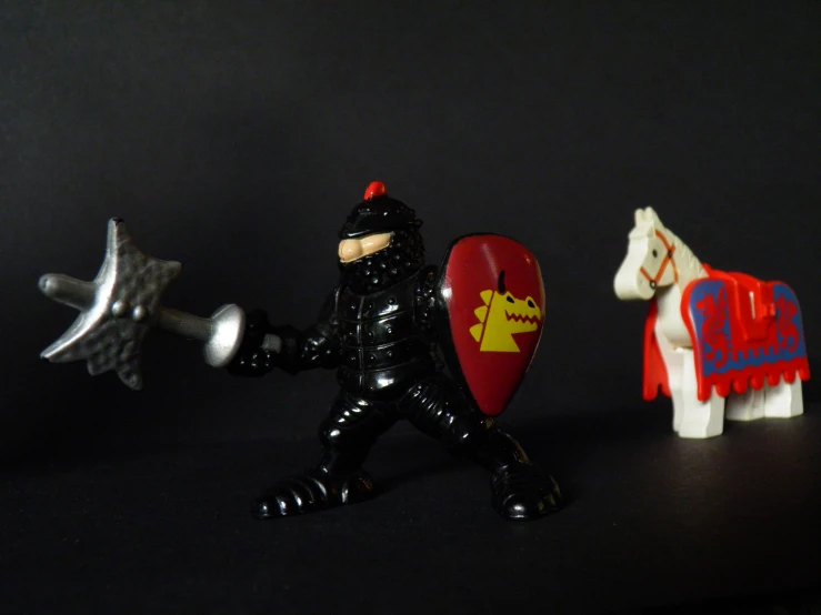 several toy figurines depicting knights, one with a shield and the other without with spears