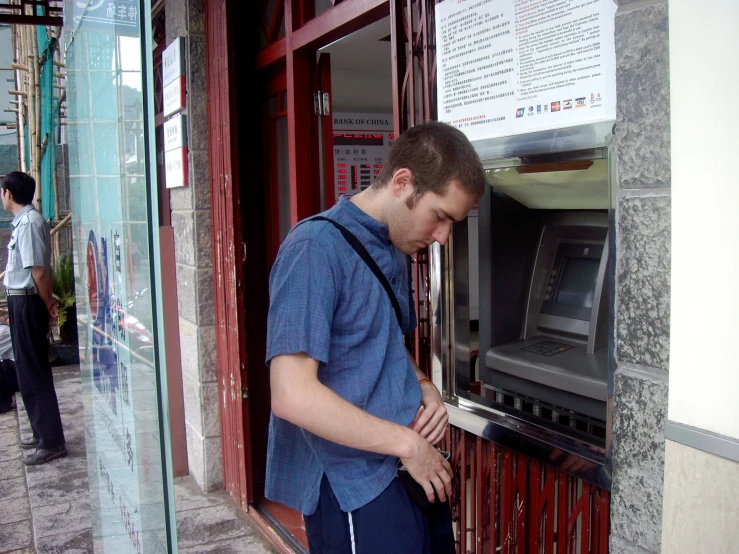 young man looking at a machine in front of a window