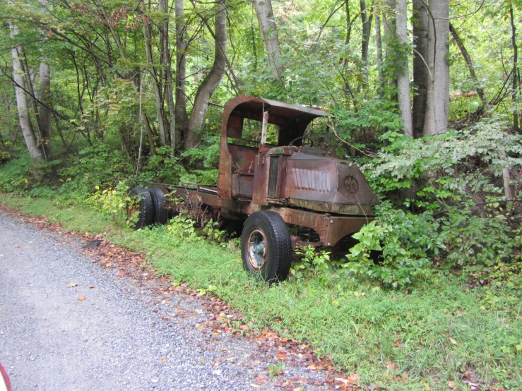 an old, rusted truck is sitting along the side of a country road