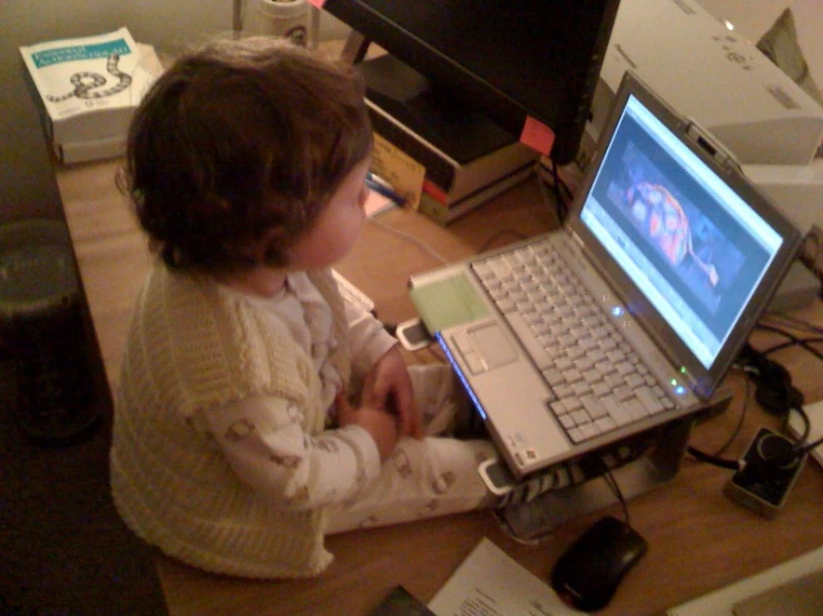 a child is sitting with her laptop on the table