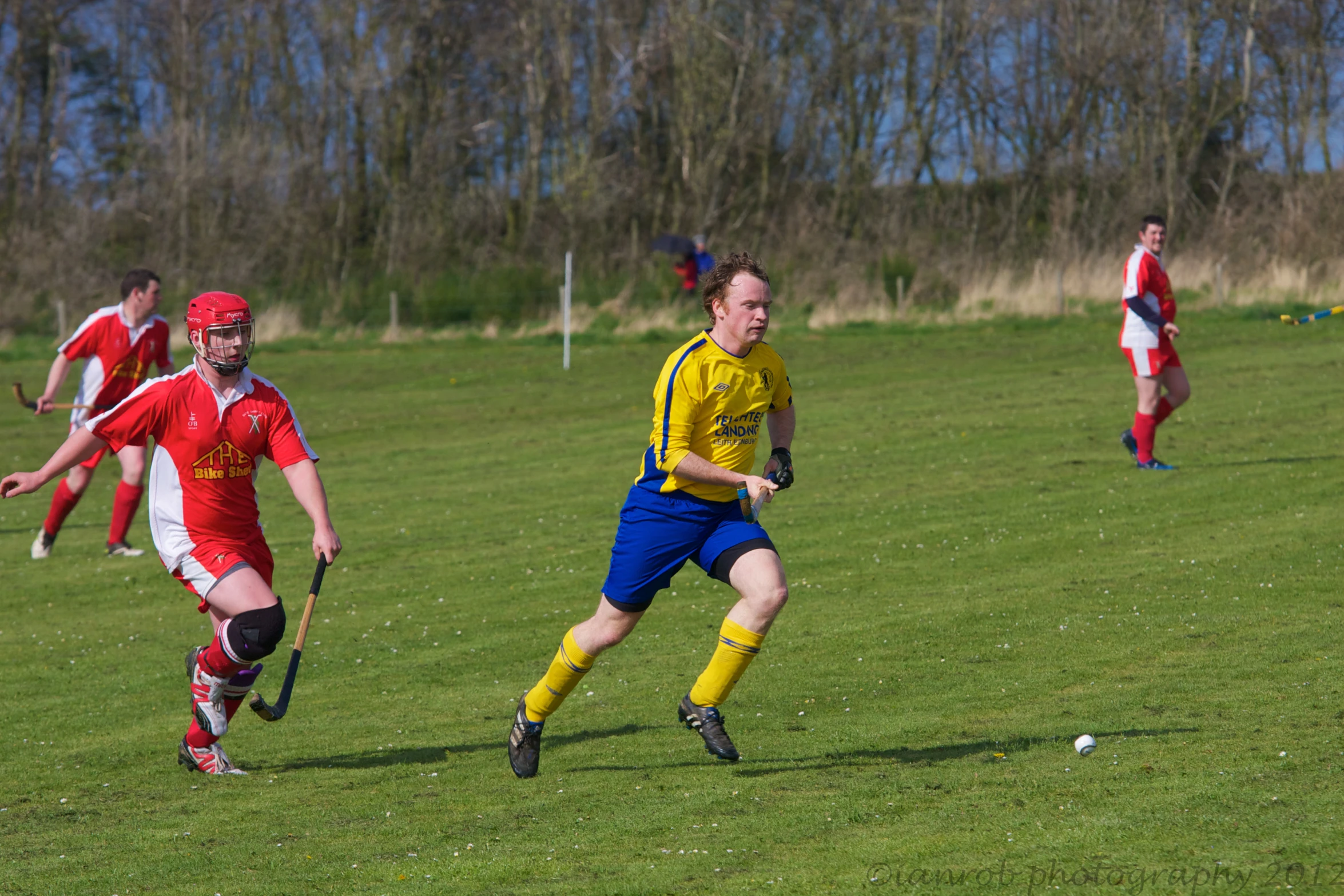 young men playing field soccer on green grass