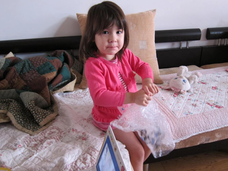 a little girl that is sitting on top of a bed