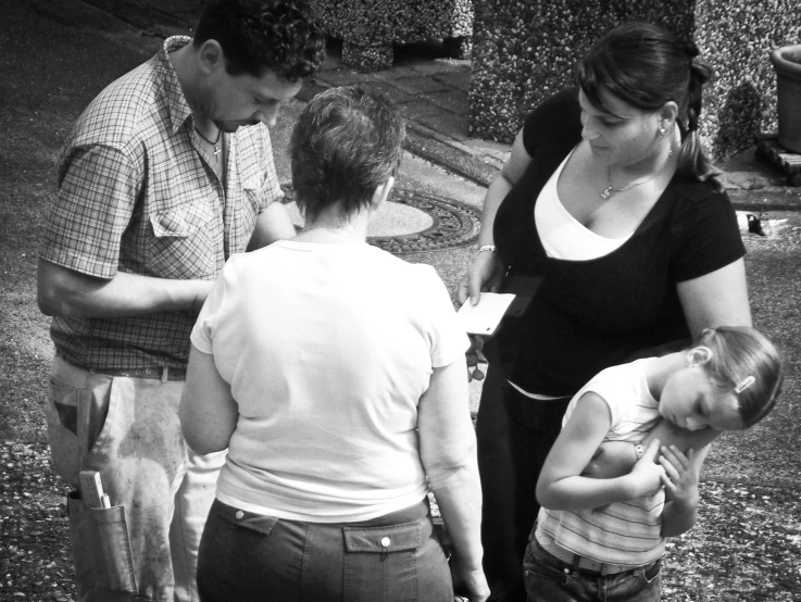 black and white pograph of four people looking at a cell phone