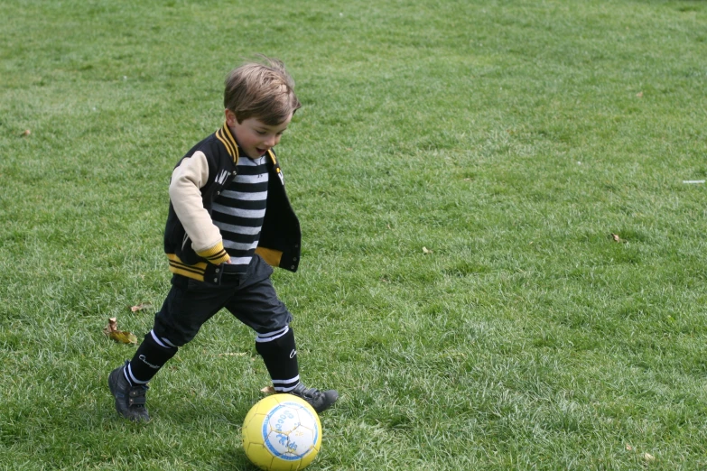 a  is standing in the grass by a soccer ball