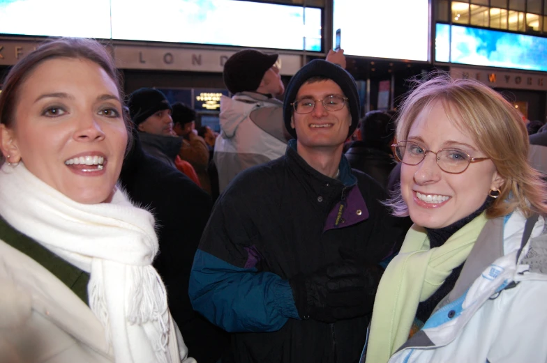 a woman standing next to a man in glasses