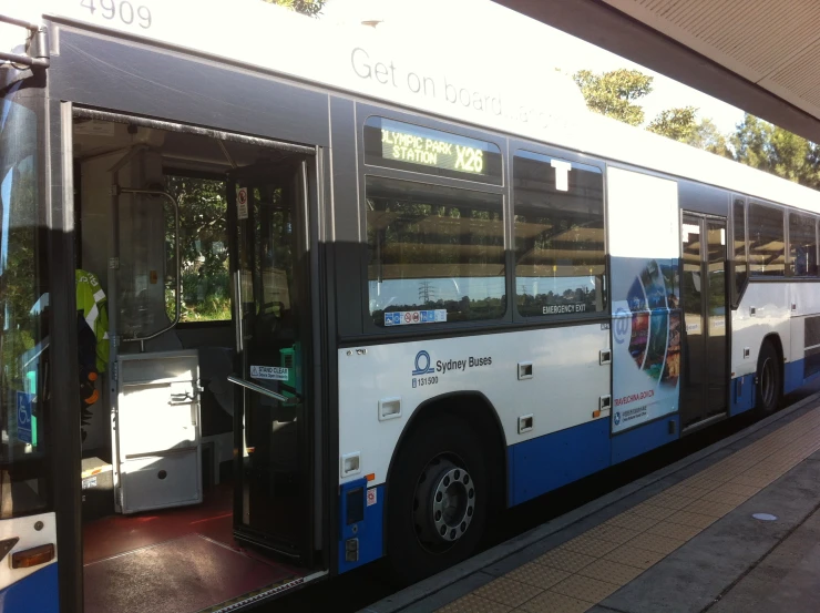 a big long black and blue bus parked at a bus stop