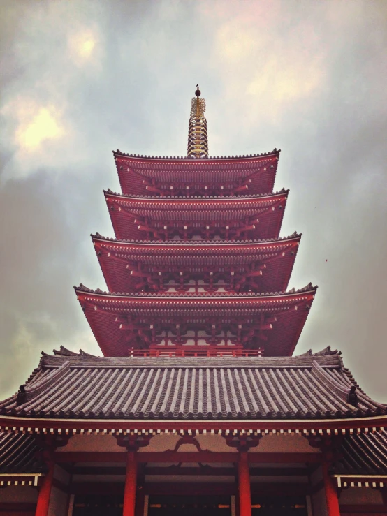 a tall, red chinese pagoda stands under a gray cloudy sky