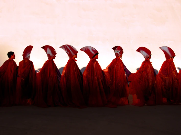 the image shows a group of women in long red dresses