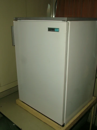 a white refrigerator freezer sitting on top of a wooden platform